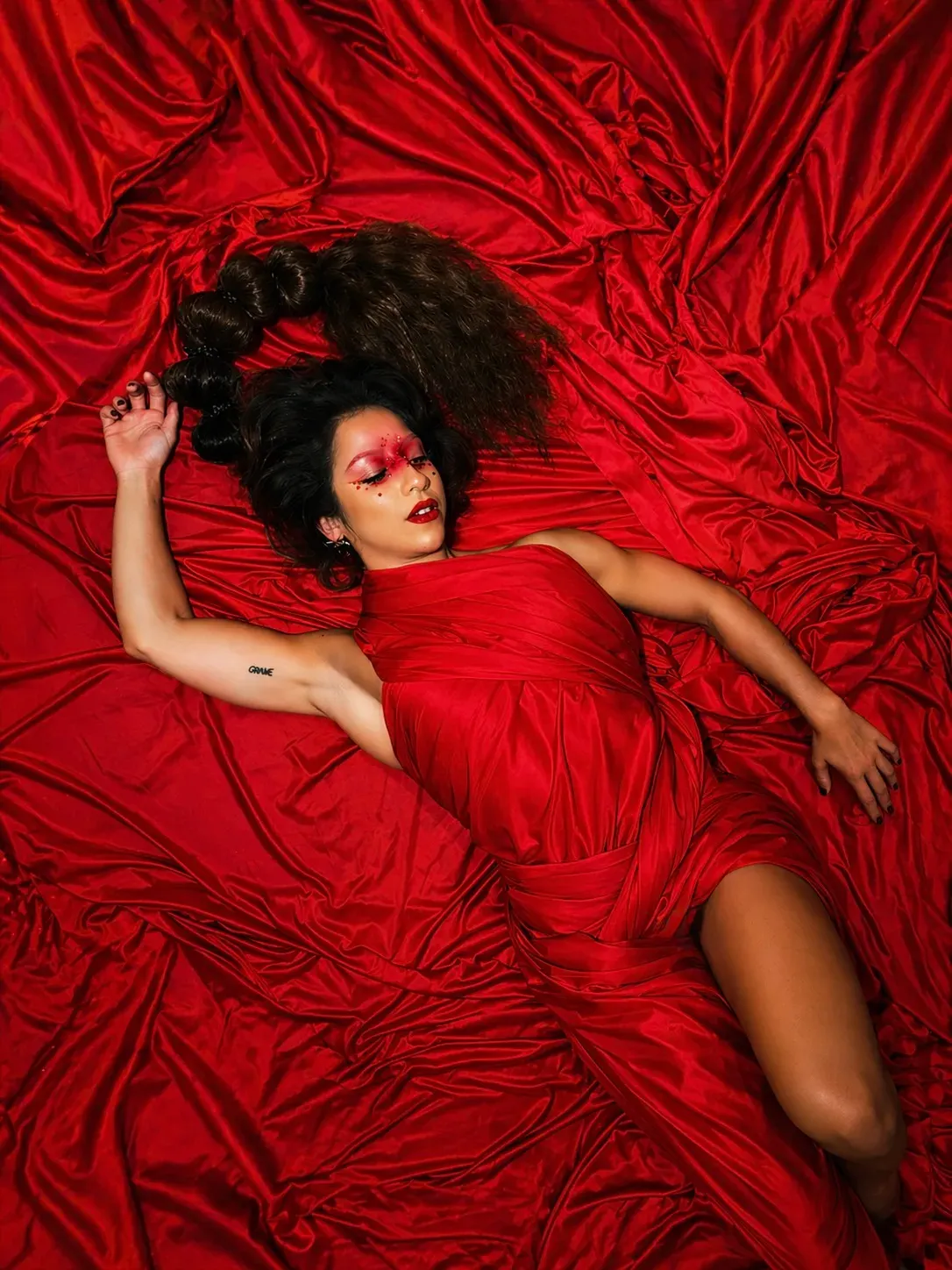 Sara Brigite lying on red silk, editorial portrait